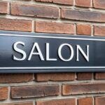 Czarny znak na ceglanej ścianie mówi "salon"
