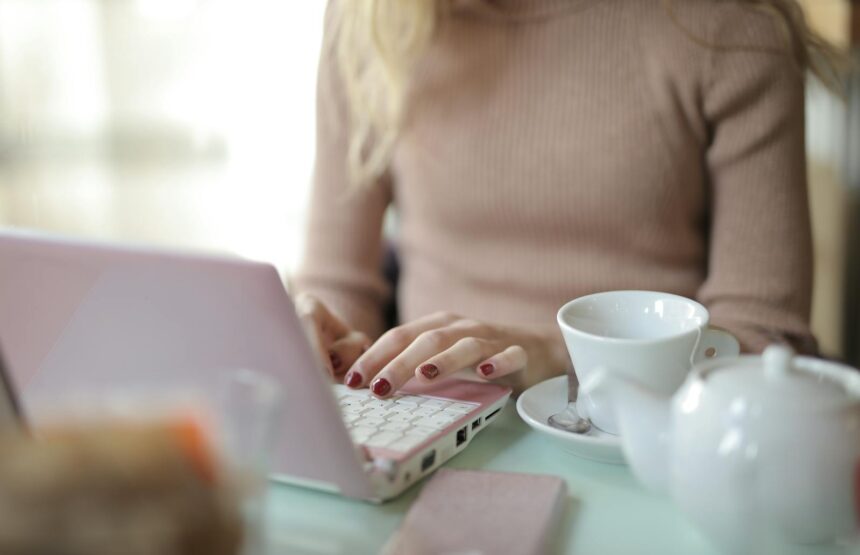 A freelancer in a cozy setting using a laptop with a cup of coffee nearby. Ideal for remote work themes.