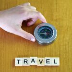 Koncepcja podróży i wakacji ręka z kompasem i słowem paszport napisane na drewnianych płytkach