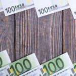 Euro banknoty kłamają ramę przy drewnianym tłem.