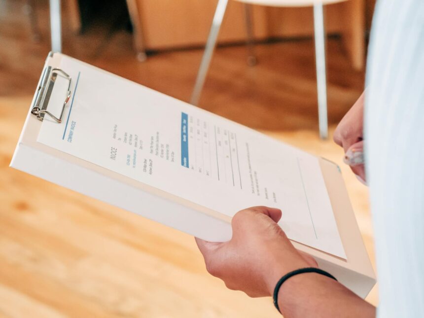 Close-up of hands holding a clipboard with business documents, indicating analysis and planning.