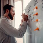 a man writing on a white board with orange markers